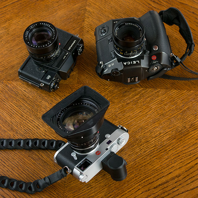 The Leicaflex (1964) film camera top left, the Leica R8 film camera (1998) with DMR digital back (2004) top right, and the "new solution", the Leica M10 (2017) with electronic viewfinder and adapter to use R lenses. 