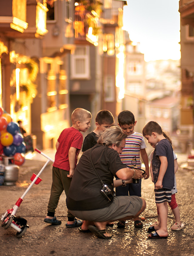 Han Delin doing street portraits of kids in Istanbul, Turkey on our "Walk with Me" sunset walk in August 2021. Leica SL2 with Leica 50mm Noctilux-M ASPH f/0.95. © Thorsten Overgaard. 